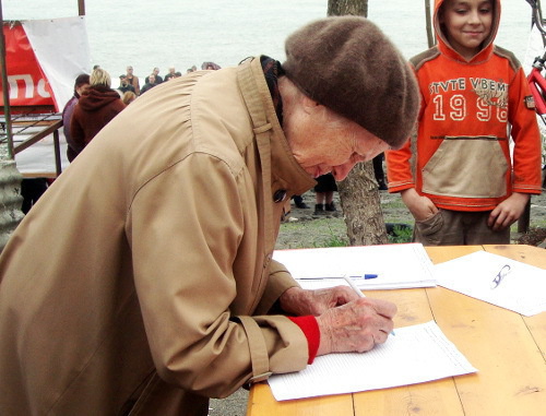 A resident of Sochi signs resolution of the rally for protection of natural beaches and parks of the Imereti Lowland against commercial developments. Sochi, April 10, 2012. Photo by Svetlana Beresteneva for the "Caucasian Knot"