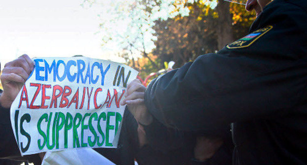 A police officer tries to take away a poster saying "Democracy in Azerbaijan is surpressed" from a protestor. Baku, 2012. Photo by Aziz Karimov for the "Caucasian Knot".