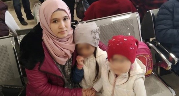 Elmira Kenzhibulatova with her children in an airport. Photo courtesy of Rasul Kenzhibulatov