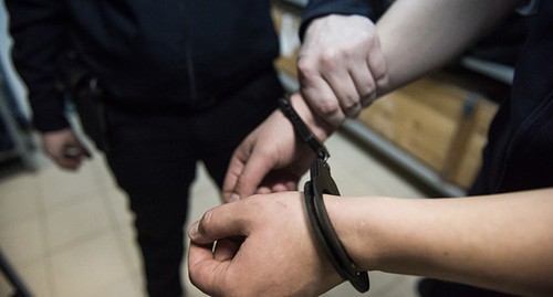 Policeman holding a detainee's hand. Photo: Elena Sineok, Yuga.ru