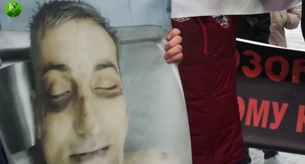 A poster showing traces of torture on Vladimir Tskaev's face. Screenshot of the video by the "Caucasian Knot" https://www.youtube.com/watch?v=1Fwh_EBWCo0