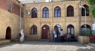 Tourists in a courtyard of a mosque in Derbent. Screenshot: https://www.youtube.com/watch?v=1rUg3LrF6kQ
