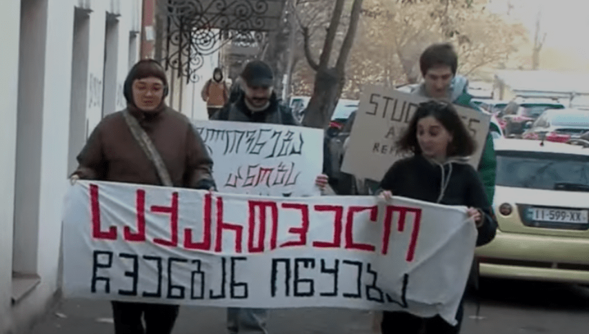Students of the Academy of Arts with a poster saying, "Georgia begins with us." Screenshot of a video posted by the “Pirveli” TV Company on January 8, 2025 https://tvpirveli.ge/ka/siaxleebi/sazogadoeba/91147-saqartvelo-itskeba-chvengan-universitetebshi-protestma-ipetqa Students of the Academy of Arts with a poster saying, "Georgia begins with us." Screenshot of a video posted by the “Pirveli” TV Company on January 8, 2025 https://tvpirveli.ge/ka/siaxleebi/sazogadoeba/91147-saqartvelo-itskeba-chvengan-universitetebshi-protestma-ipetqa